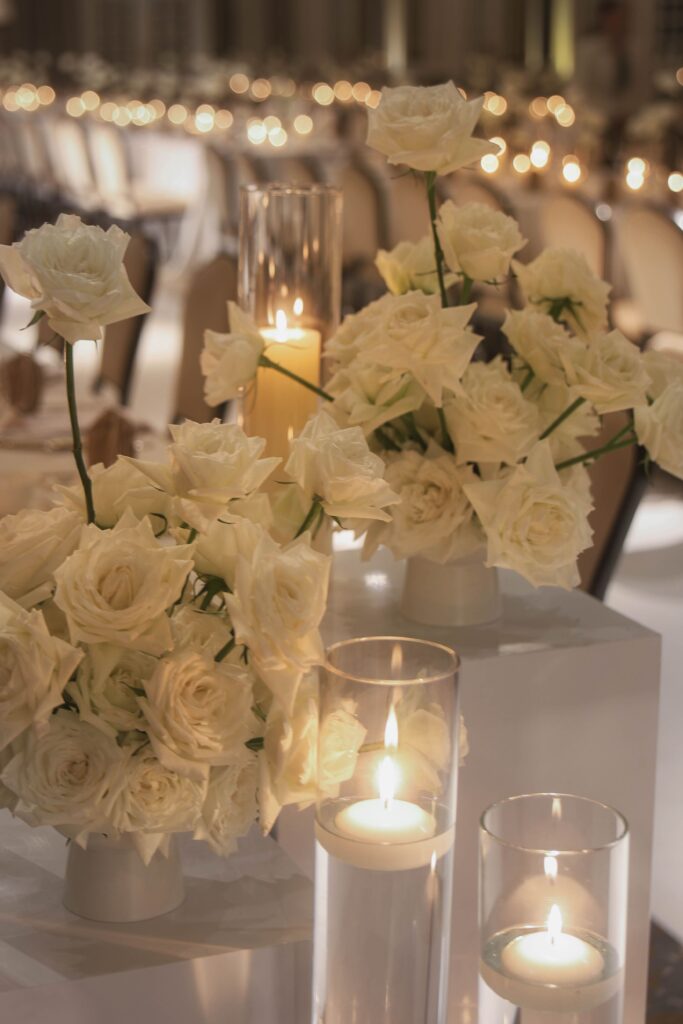 White rose floral arrangement styled on pedestal with candlelight for minimalist wedding decor at Raffles Hotel Singapore