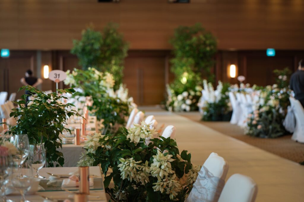 Ballroom guest seating framed by abundant organic floral arrangements in soft pastel shades at The Ritz-Carlton Singapore