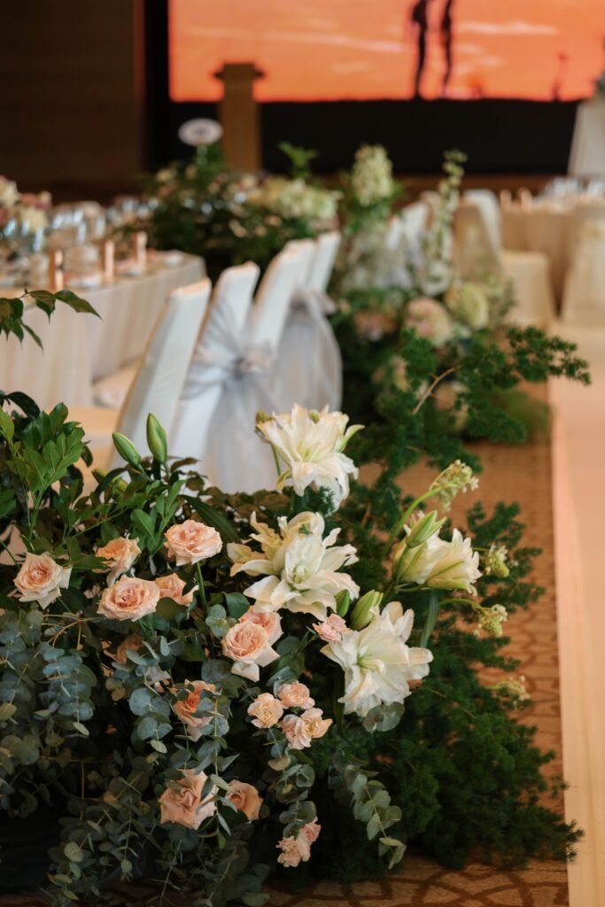 Tall floral pillar arrangement with white blooms, blush roses and textured greenery creating vertical presence in the ballroom at The Ritz-Carlton Singapore