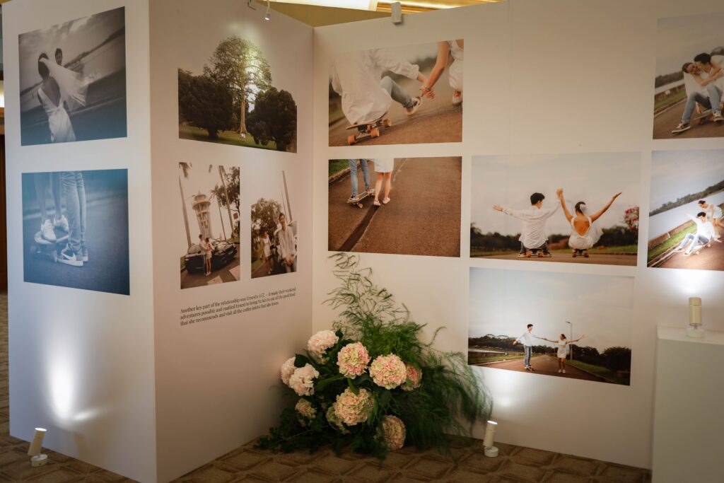 Structured exhibition-style wedding photo gallery with floral accents creating a narrative journey in the foyer at The Ritz-Carlton Singapore