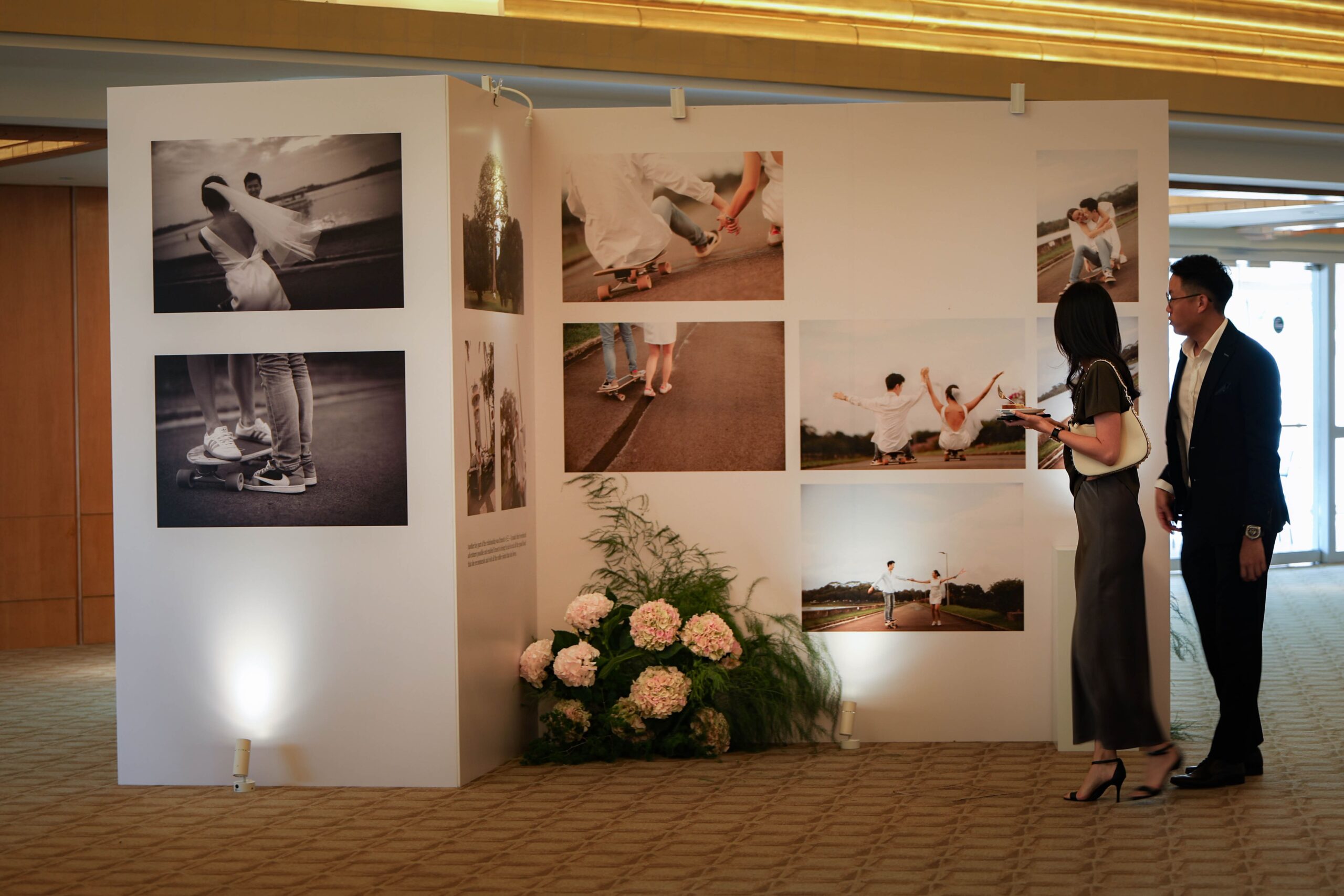 Curated wedding photo gallery exhibition with milestone images and floral accents styled as a memory lane at The Ritz-Carlton Singapore