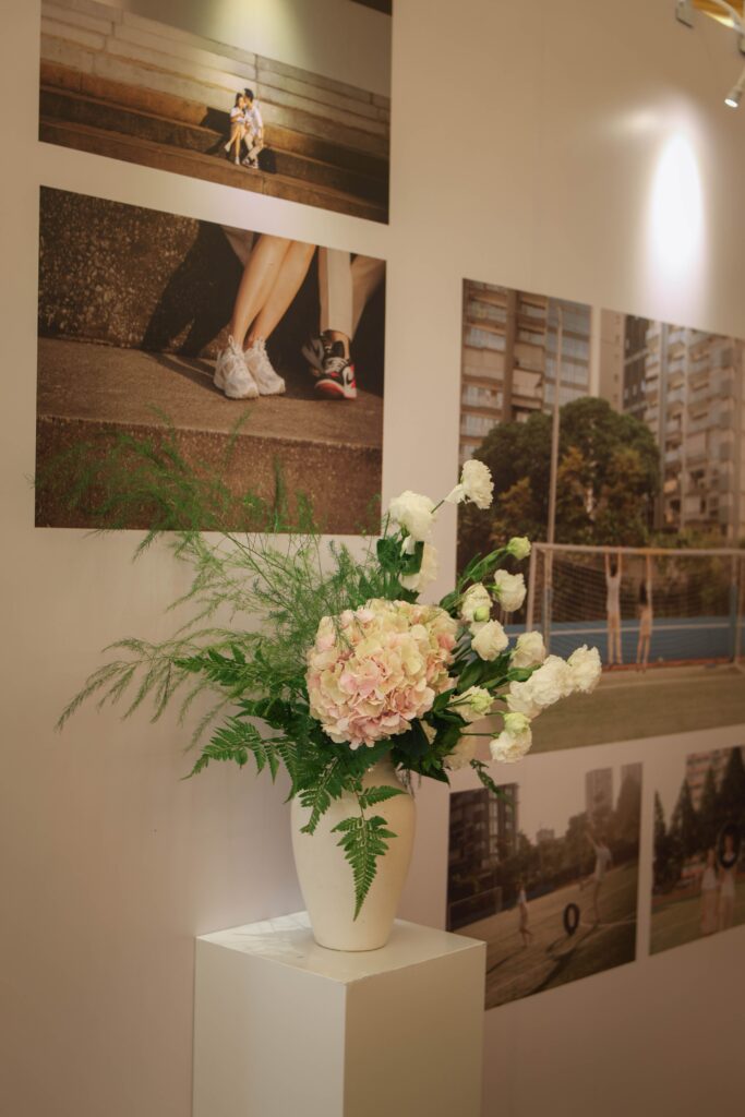 Pedestal floral arrangement with blush roses, white hydrangeas and greenery accenting a curated wedding photo gallery at The Ritz-Carlton Singapore