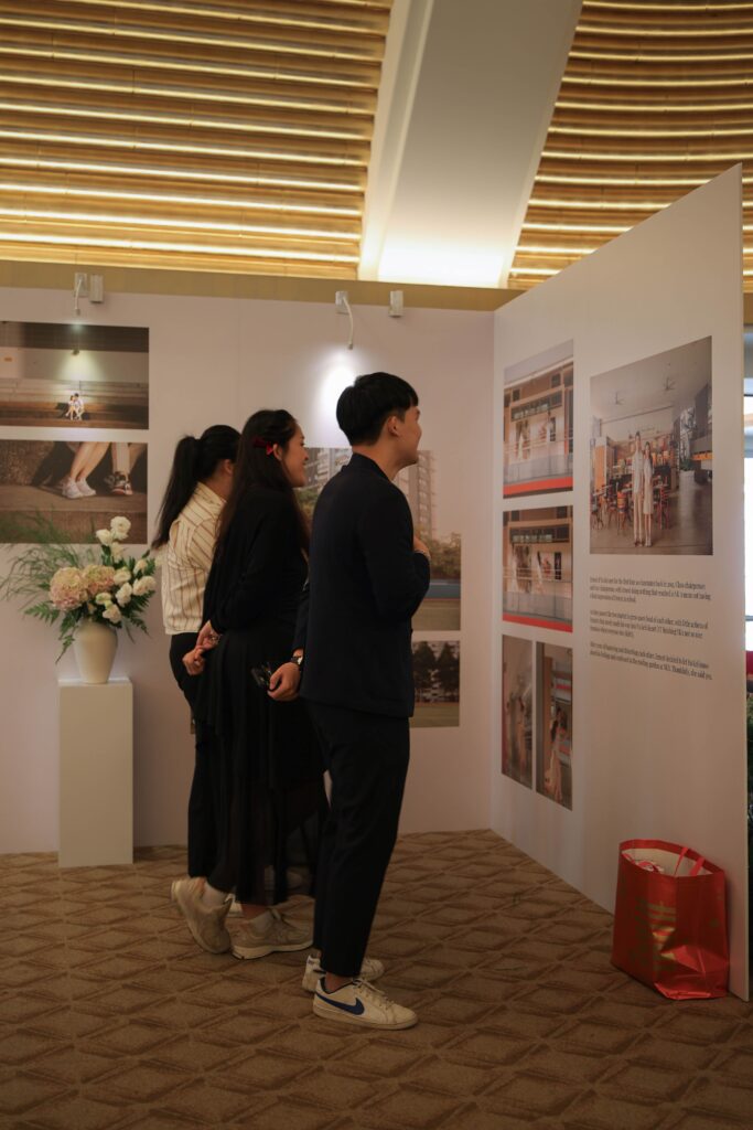 Guests viewing a curated wedding photo gallery exhibition surrounded by soft romantic floral arrangements at The Ritz-Carlton Singapore