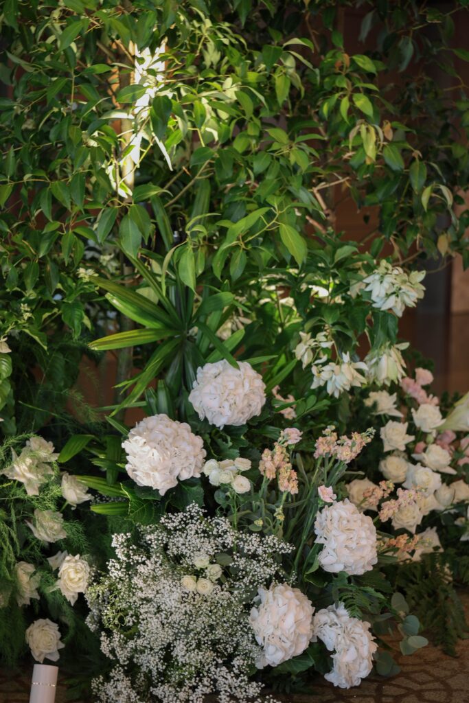 Lush greenery installation with white and blush florals creating a natural garden atmosphere inside the ballroom at The Ritz-Carlton Singapore