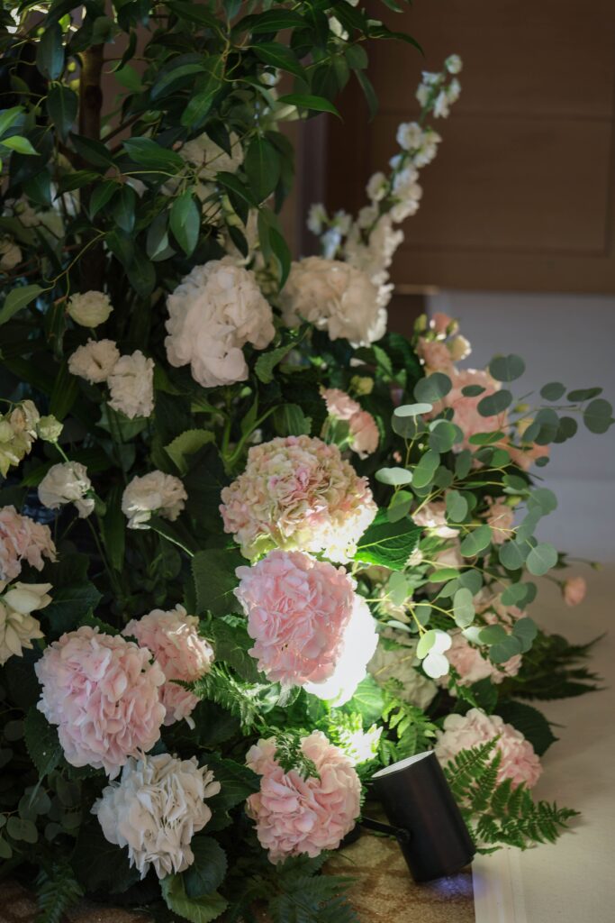 Tall garden-style floral installation with hydrangeas, roses and textured foliage softening the ballroom interior at The Ritz-Carlton Singapore