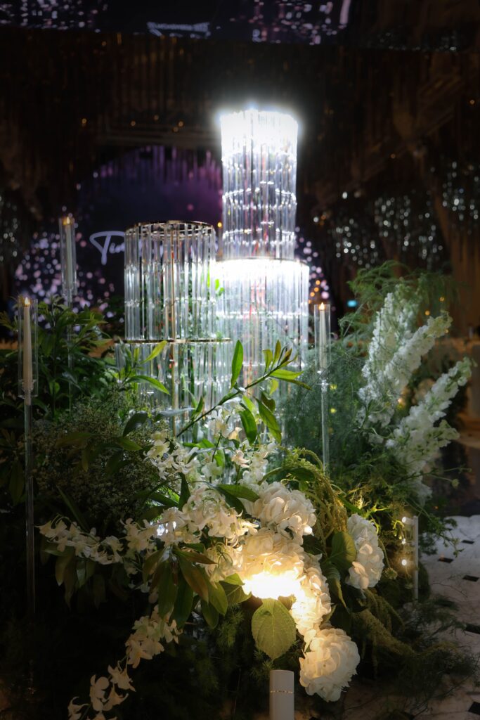 Crystal chandelier installation surrounded by white hydrangeas, delphinium, baby’s breath and lush greenery arranged in a garden style floral installation for a candlelit romantic ballroom wedding at JW Marriott Hotel Singapore