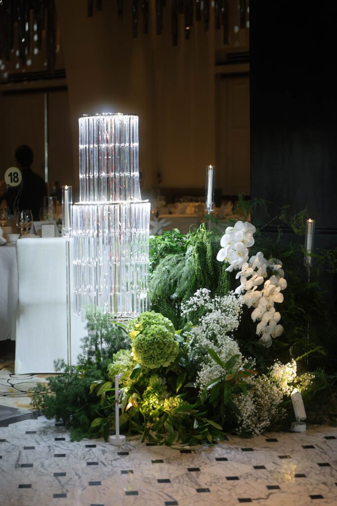 Tall crystal chandelier centerpiece styled with white hydrangeas, delphinium, baby’s breath and lush greenery floral arrangements creating an elegant candlelight wedding decoration at JW Marriott Hotel Singapore