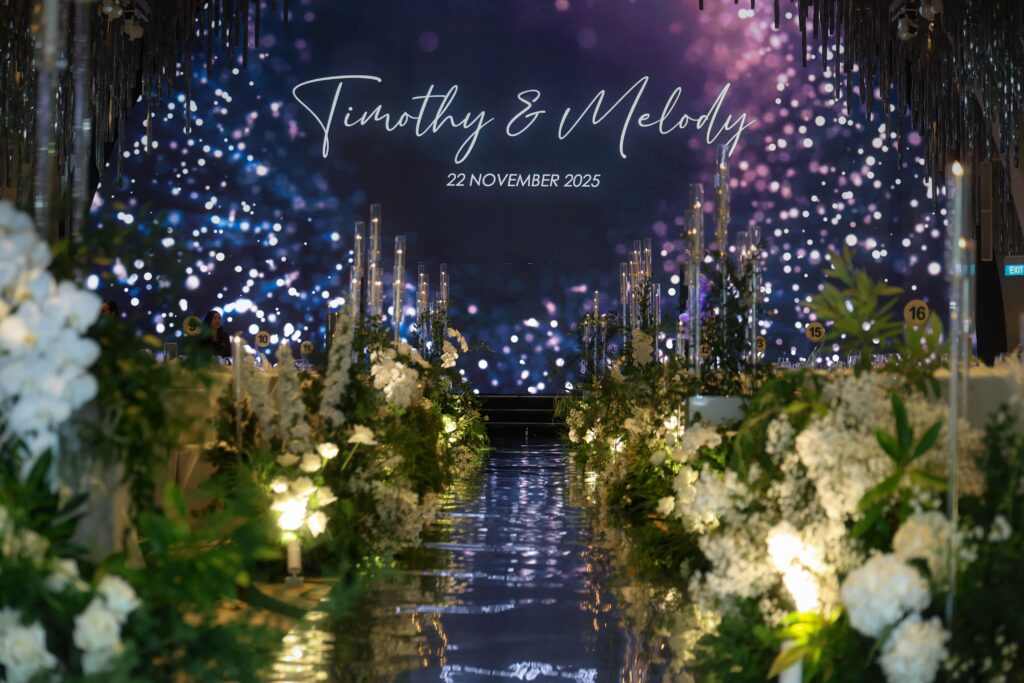White and green wedding aisle with lush floral styling and candlelight creating a magical romantic ballroom entrance at JW Marriott Hotel Singapore