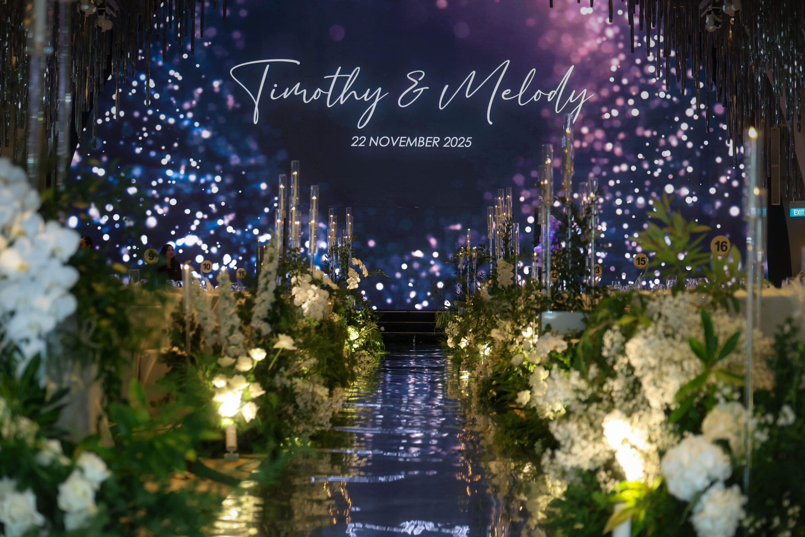 White and green wedding aisle with lush floral styling and candlelight creating a magical romantic ballroom entrance at JW Marriott Hotel Singapore