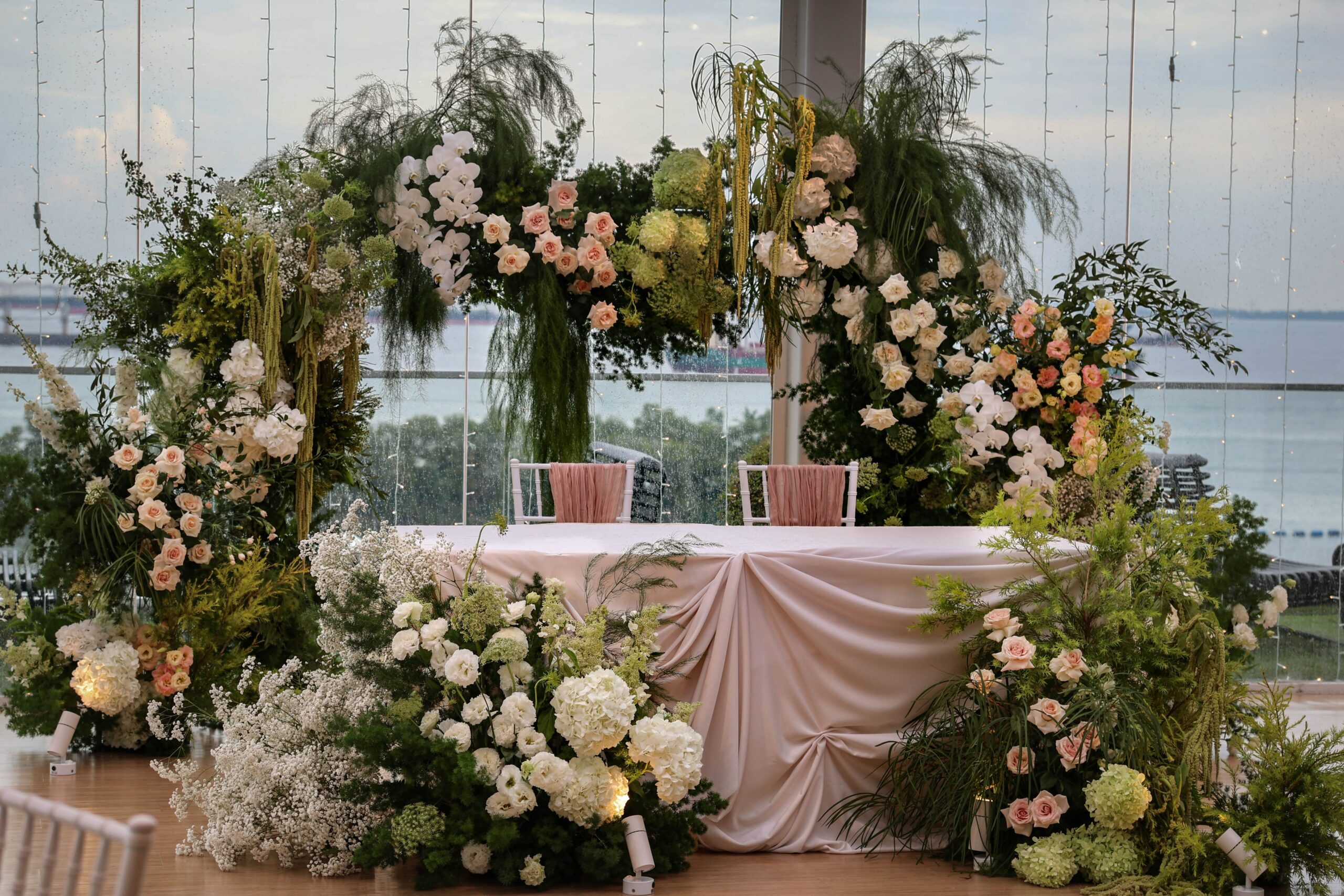Full view of romantic garden-style floral ceremony installation with roses, orchids, lisianthus, hydrangeas, and greenery framing the wedding stage at Sky Garden Sentosa, Sentosa Singapore
