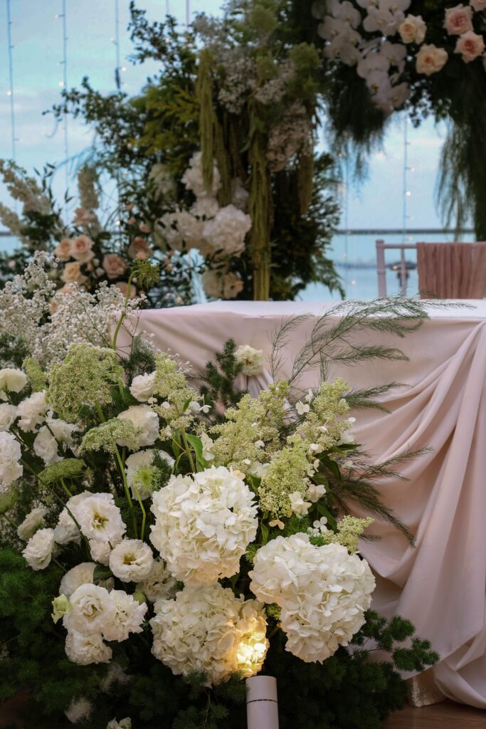 Lush ceremony base arrangement with white hydrangeas, roses, lisianthus, and layered greenery styled in a soft garden arrangement at Sky Garden Sentosa, Sentosa Singapore