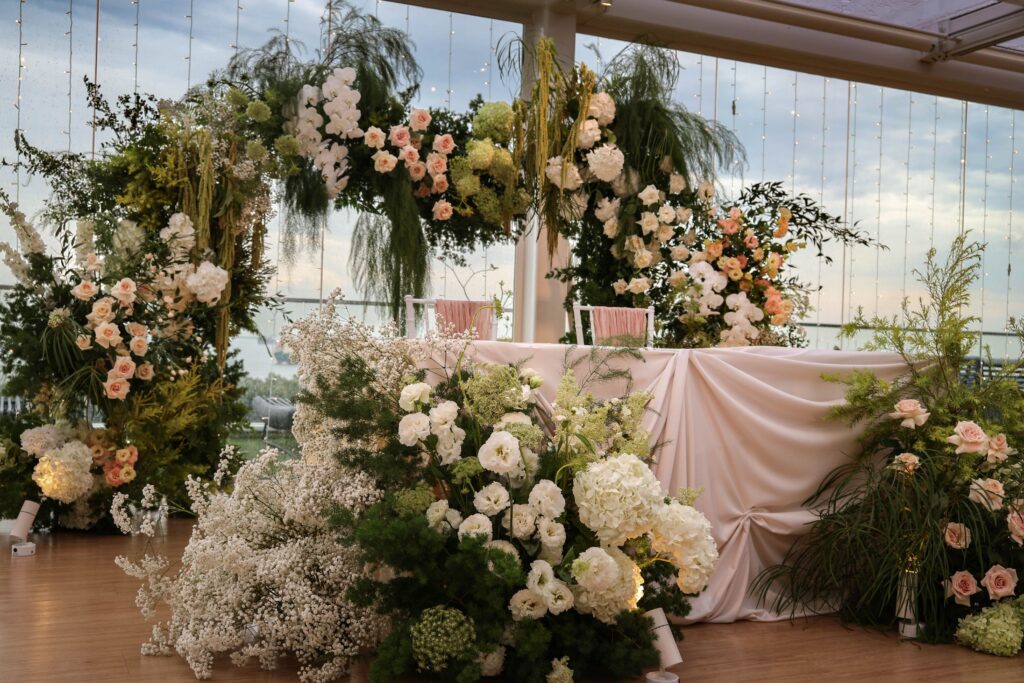 Ceremony stage floral arrangement with lush greenery, white flowers, and garden textures placed beside the couple’s table at Sky Garden Sentosa, Sentosa Singapore