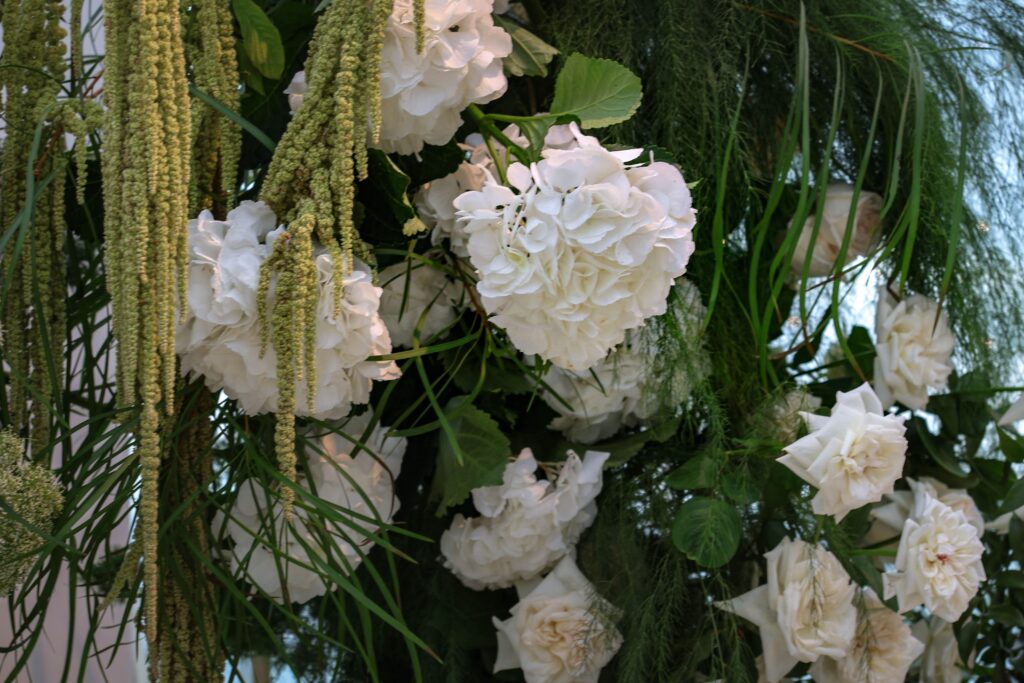 Ceremony arch design featuring cascading amaranthus with white hydrangeas, roses and garden foliage arranged in an airy organic style at Sky Garden Sentosa, Sentosa Singapore