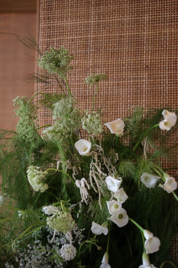 Soft white floral arrangement with calla lilies, layered greenery, and natural woven textures styled in a refined modern romantic design at Min Jiang at Dempsey, Singapore