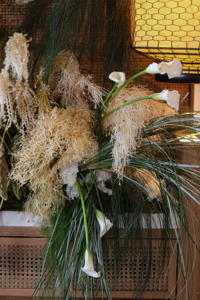 Earth-toned pampas grass, cascading calla lilies, and lush green foliage arranged into a warm textural floral backdrop design at Min Jiang at Dempsey, Singapore