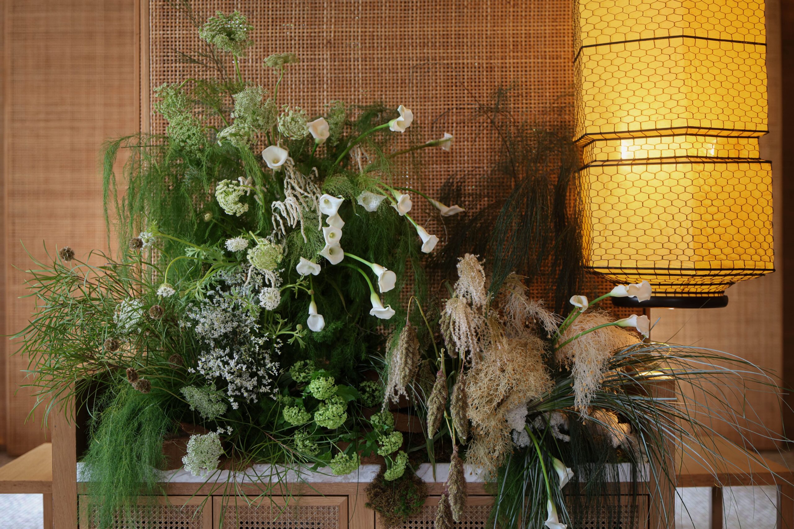 Elegant white and green floral feature with airy foliage, pampas textures, and earthy layered styling creating a warm modern romantic installation at Min Jiang at Dempsey, Singapore