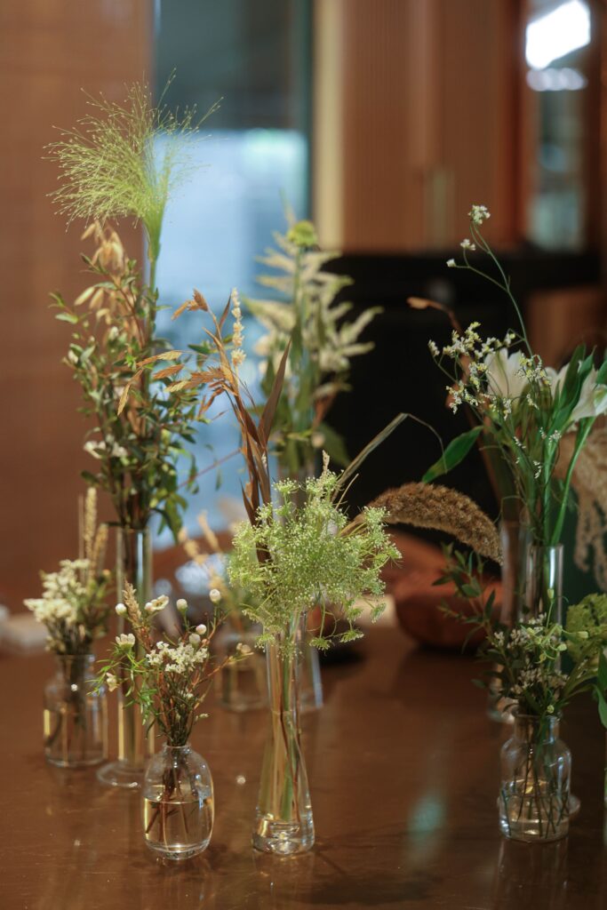 Elevated glass vase centrepieces with airy white flowers and soft foliage creating refined understated wedding table styling at Min Jiang at Dempsey, Singapore
