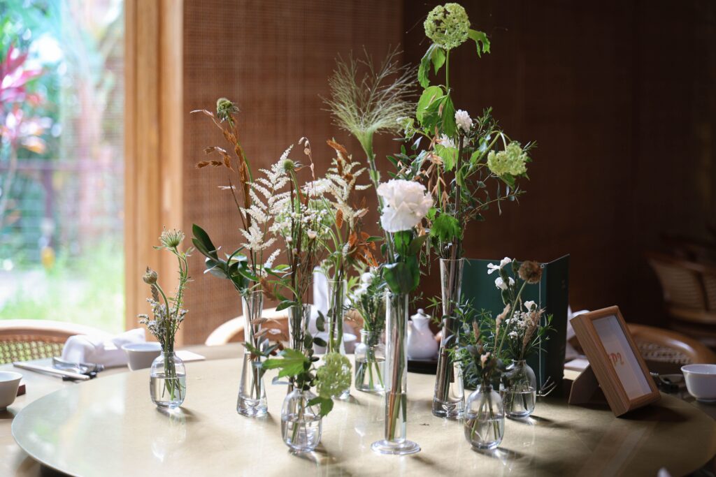 Minimalist wedding tablescape with floating white blooms, delicate foliage stems, and elegant glass vase styling for intimate dining celebration at Min Jiang at Dempsey, Singapore