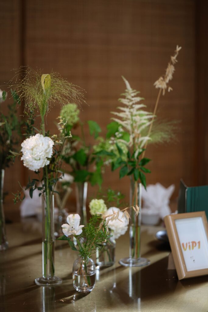 Modern romantic reception centrepieces with white roses, glass vessels, and delicate green stems styled for elegant intimate dining at Min Jiang at Dempsey, Singapore