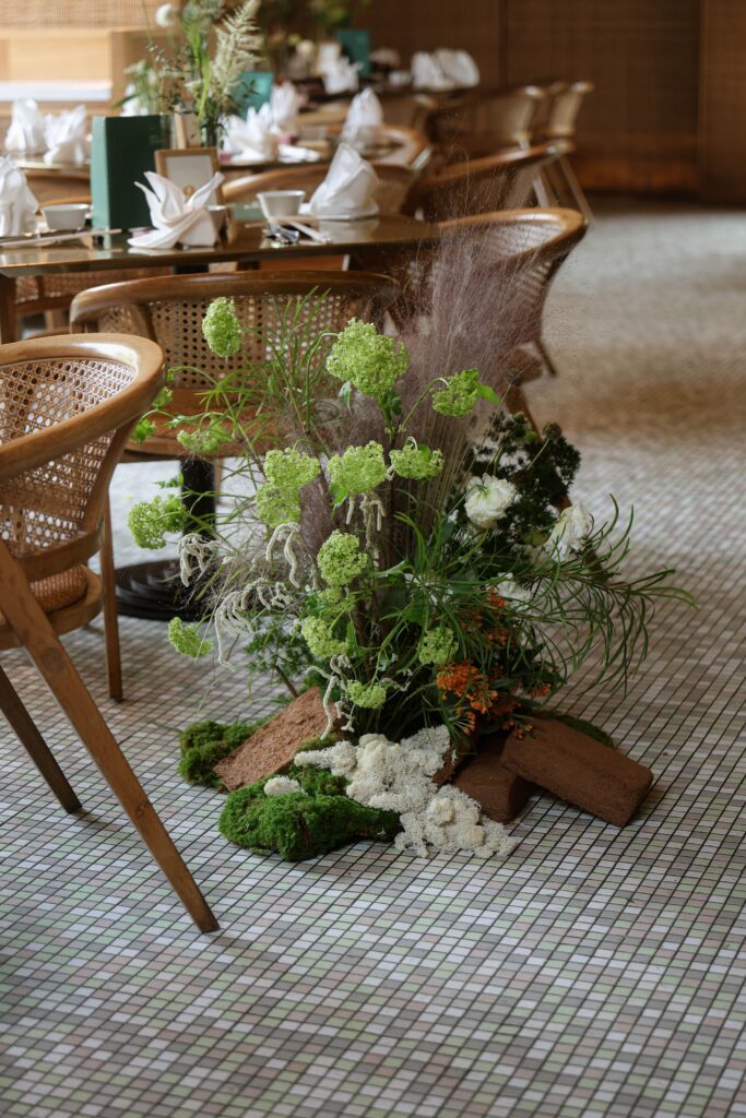 Organic floor floral styling with lush greenery, natural wood textures, and white blooms creating intimate restaurant wedding atmosphere at Min Jiang at Dempsey, Singapore