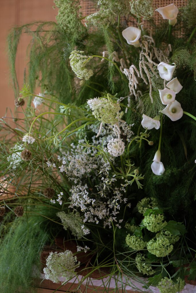 Organic white calla lilies, textured greenery, hydrangeas, and wispy grasses arranged in an earthy sculptural floral installation at Min Jiang at Dempsey, Singapore