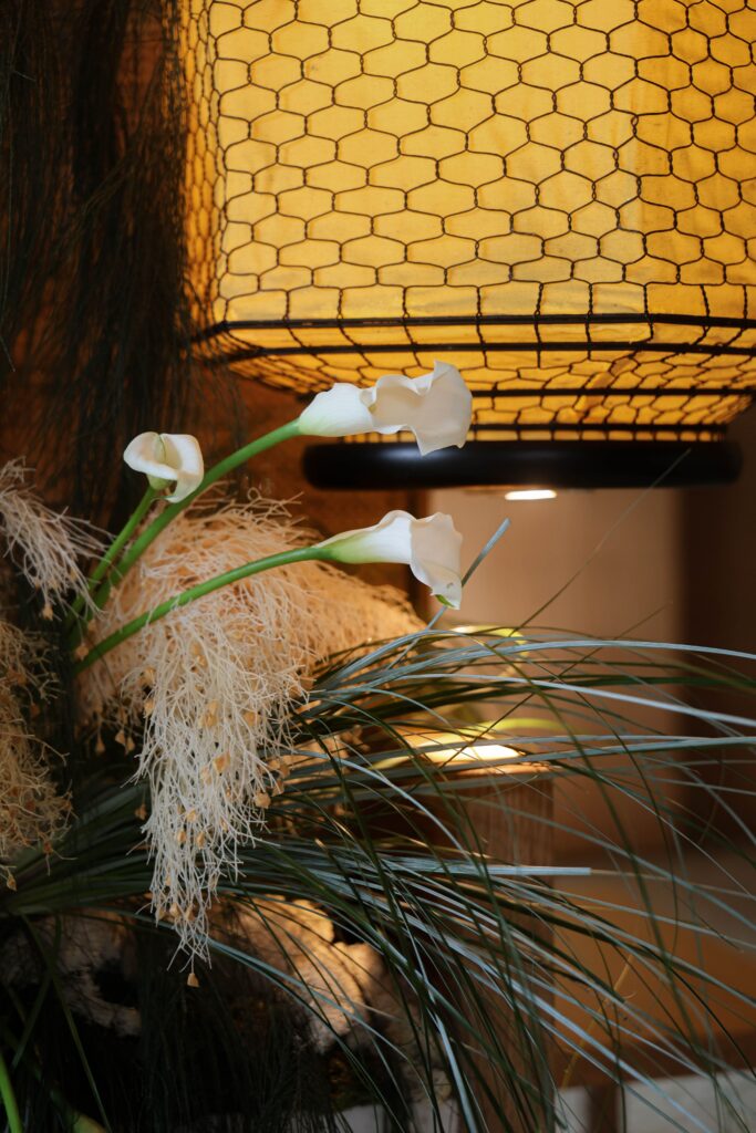 Pampas grass, white calla lilies, and flowing botanical textures framed against ambient warm lighting in romantic restaurant styling at Min Jiang at Dempsey, Singapore