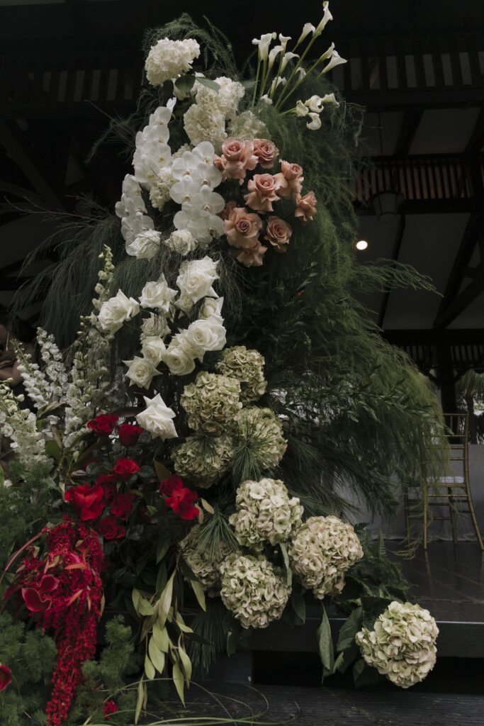 Close-up floral arrangement with white hydrangeas, blush roses, burgundy florals, and layered greenery styled in an organic modern classic wedding design at Raffles Hotel Singapore