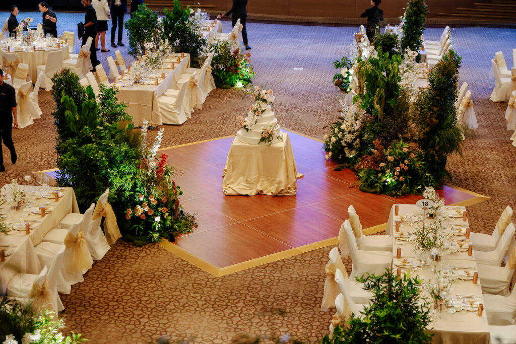 Central dance floor surrounded by tall tree installations and lush greenery with subtle floral accents, creating a woodland-inspired immersive layout at The Ritz-Carlton Millenia Singapore