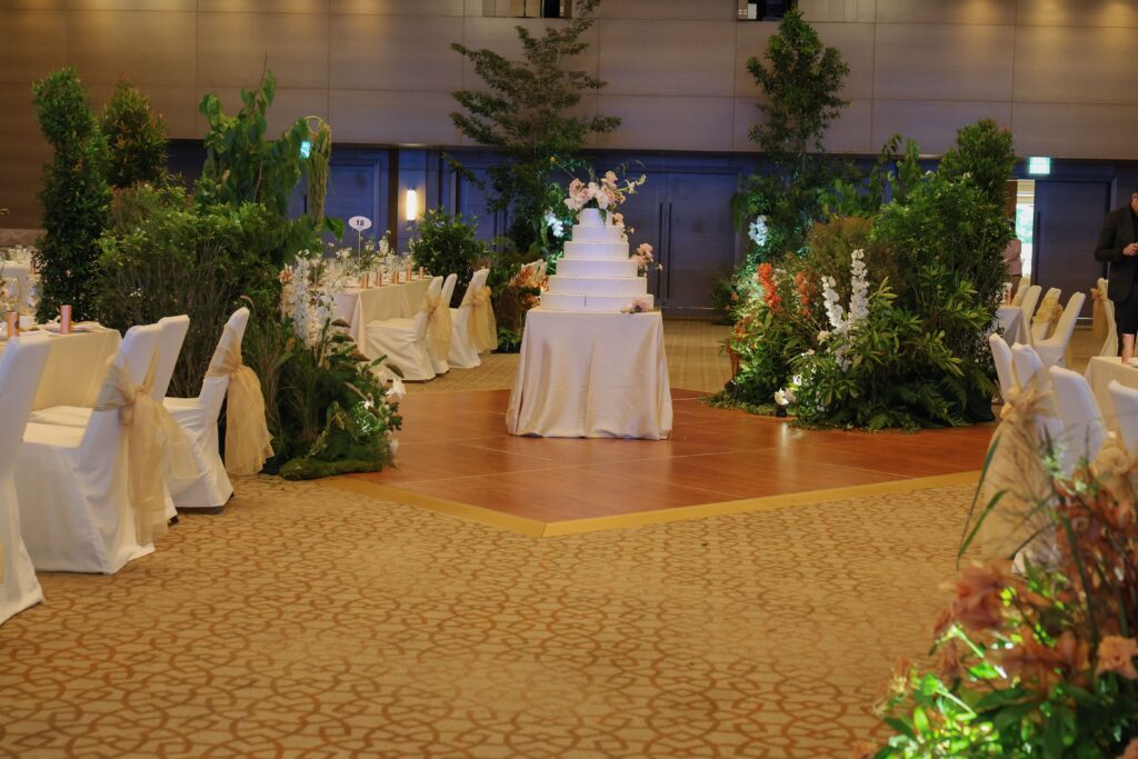 Forest-inspired entrance with tall tree-like installations, natural greenery, and soft floral accents creating an “in the woods” atmosphere leading into the dance floor at The Ritz-Carlton Millenia Singapore