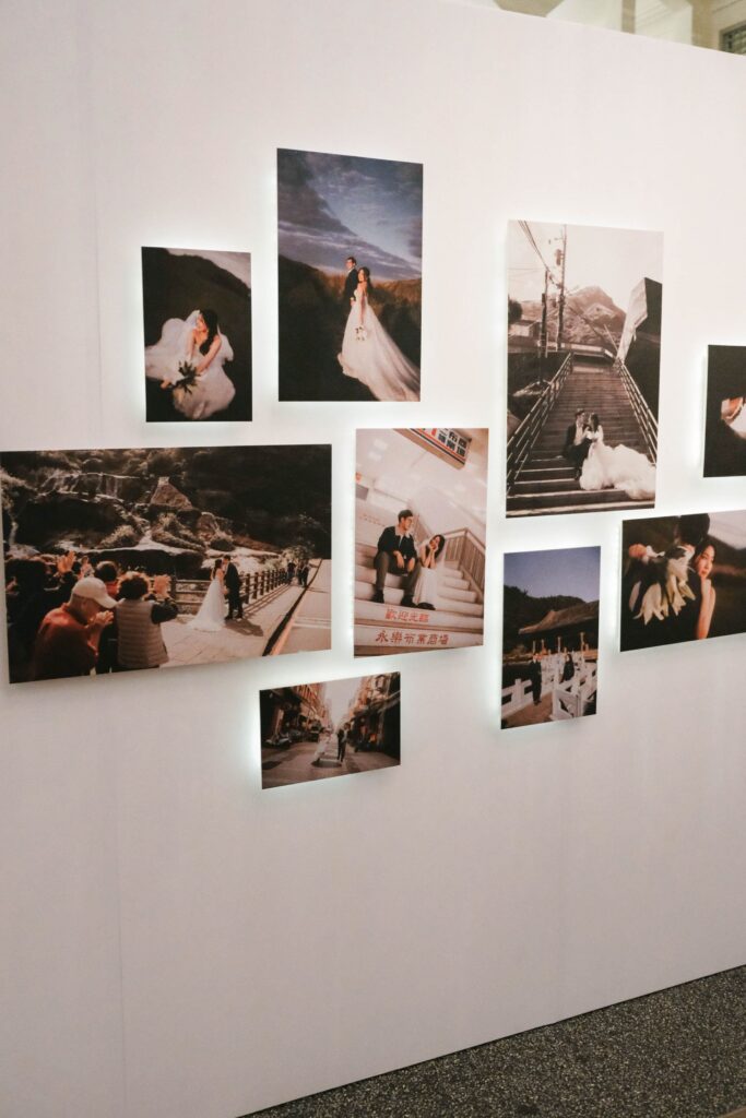 Side view of a photo gallery display integrated into a privacy wall design within a white and green wedding setup, The Clifford Pier Singapore