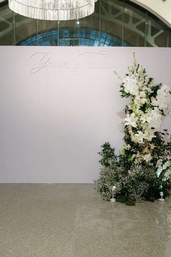 White and green floral arrangement placed beside a structured privacy wall design with soft greenery accents, The Clifford Pier Singapore