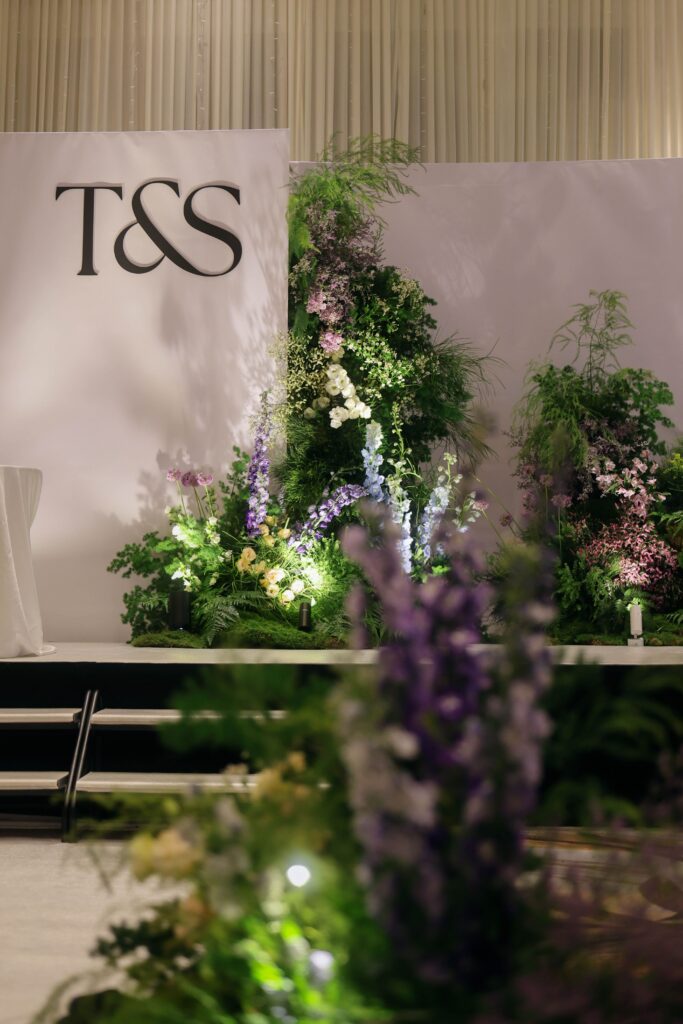 Layered stage backdrop with abundant greenery, wildflower-inspired floral arrangements, and asymmetrical composition creating an alpine-inspired wedding setting at Westin Singapore.