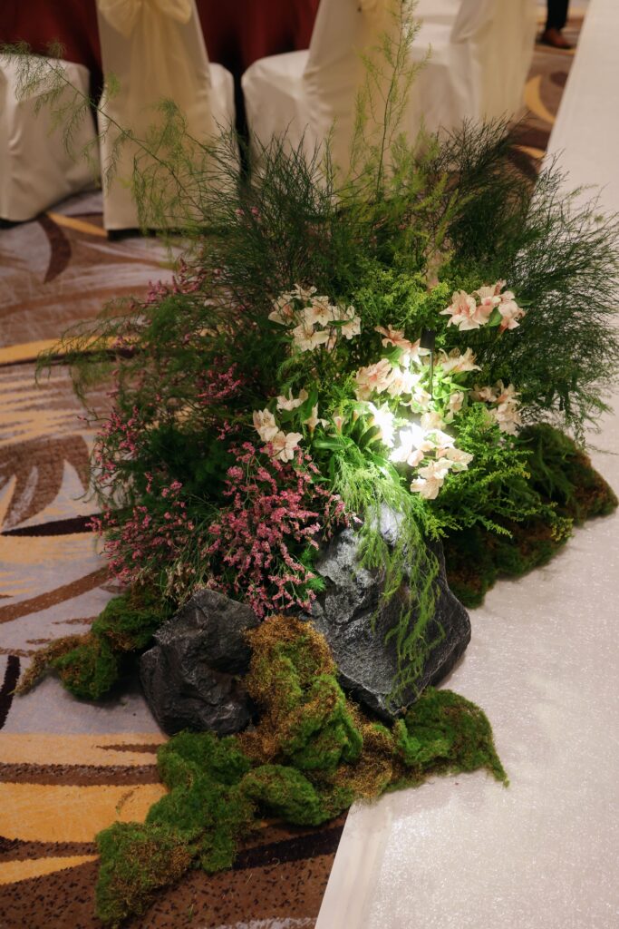 Asymmetrical aisle floral installation with textured greenery, pastel wildflowers, moss, and rocks arranged to reflect the beauty of nature at Westin Singapore.