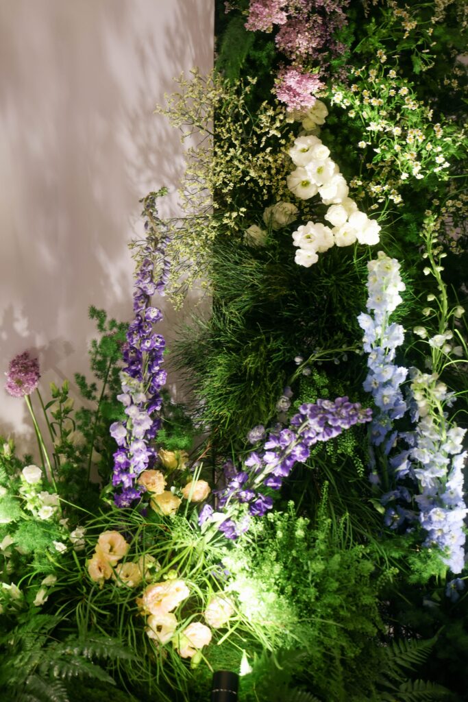 Close-up of mountain-inspired floral installation with delphiniums, white blooms, layered greenery, and organic asymmetrical styling reflecting alpine landscapes at Westin Singapore.
