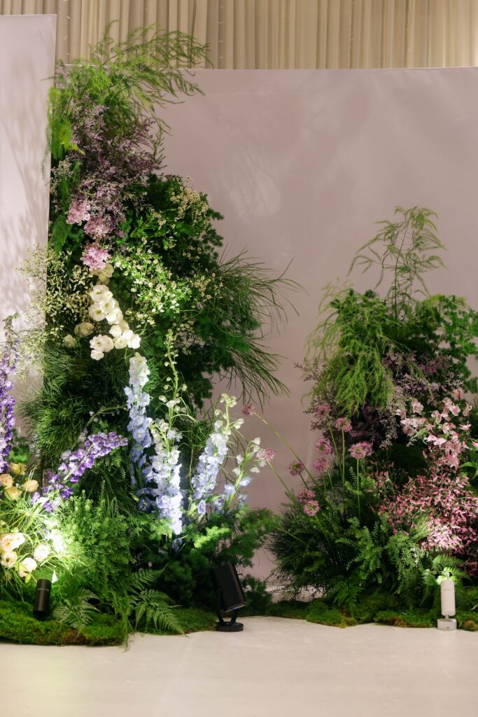 Full view of layered stage floral installation with wildflowers, lush greenery, asymmetrical composition, and mountain-inspired styling for a personalised wedding at Westin Singapore.