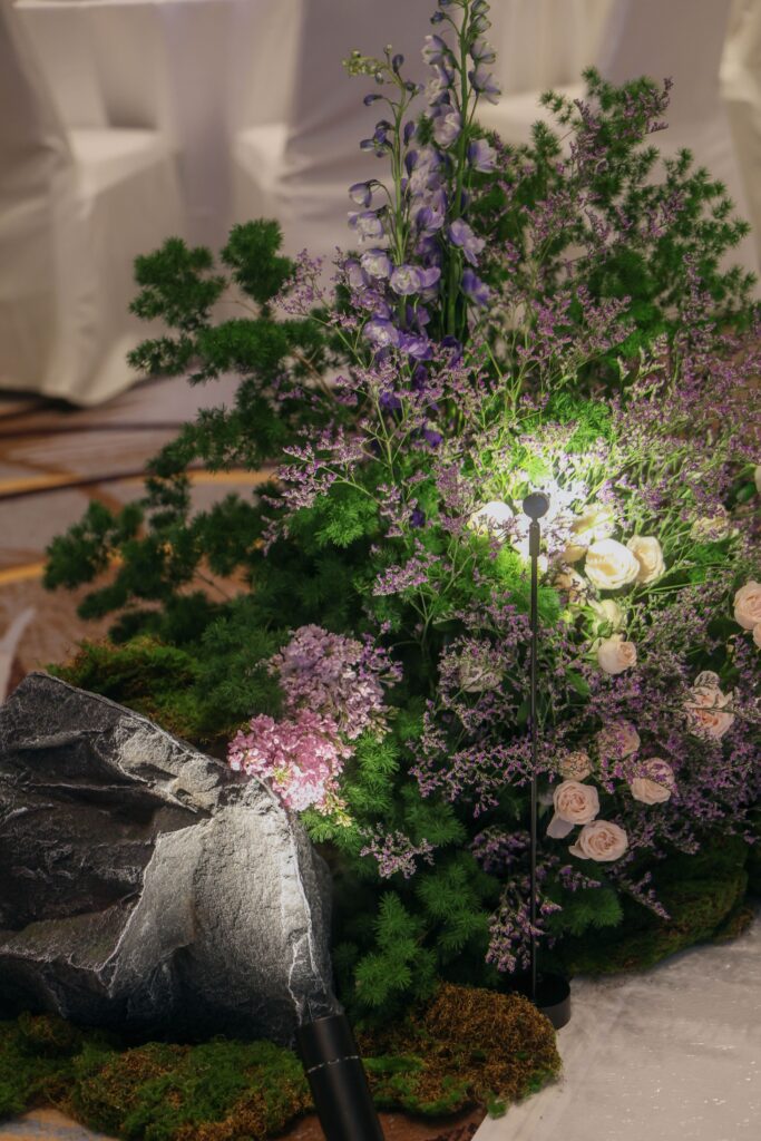 Organic nature-inspired aisle floral arrangement featuring lavender blooms, layered greenery, natural rocks, and moss creating a nature-inspired wedding atmosphere at Westin Singapore.