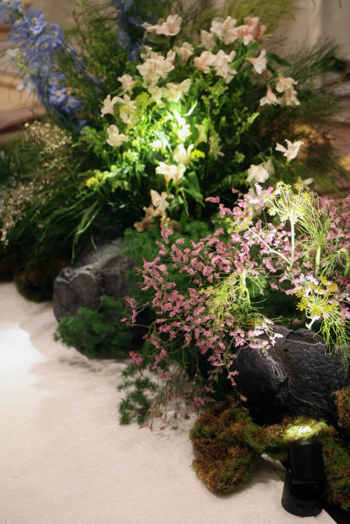 Wildflower aisle decoration with layered seasonal blooms, lush foliage, moss accents, and natural stone elements creating an organic hiking trail aesthetic at Westin Singapore.