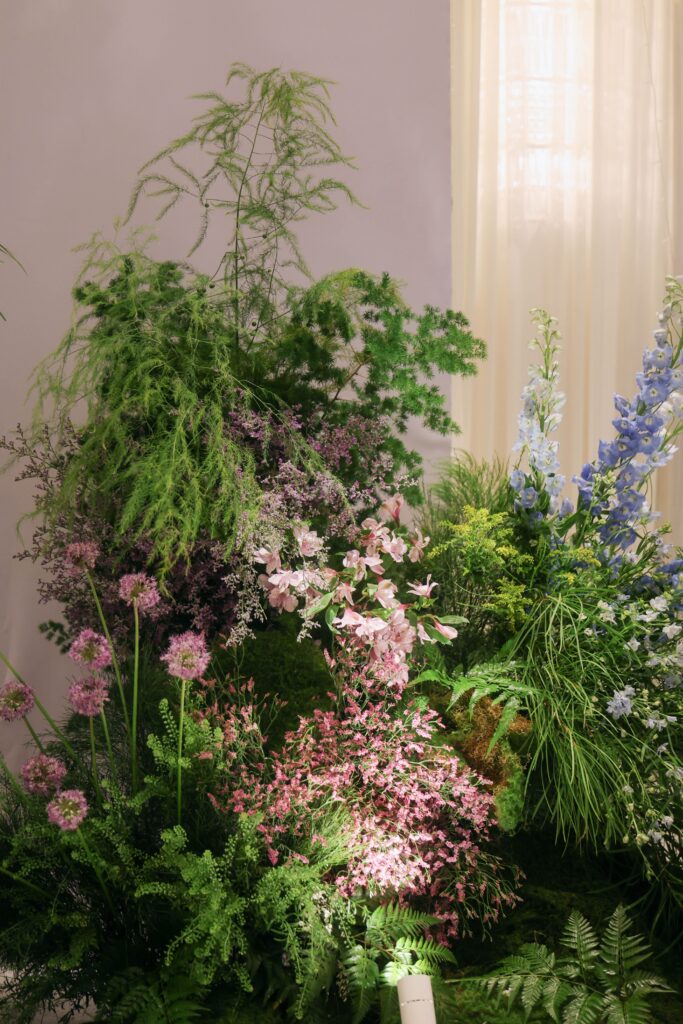 Wildflower-inspired stage floral arrangement with pastel blooms, tall greenery, and natural layered composition creating an organic garden aesthetic at Westin Singapore.