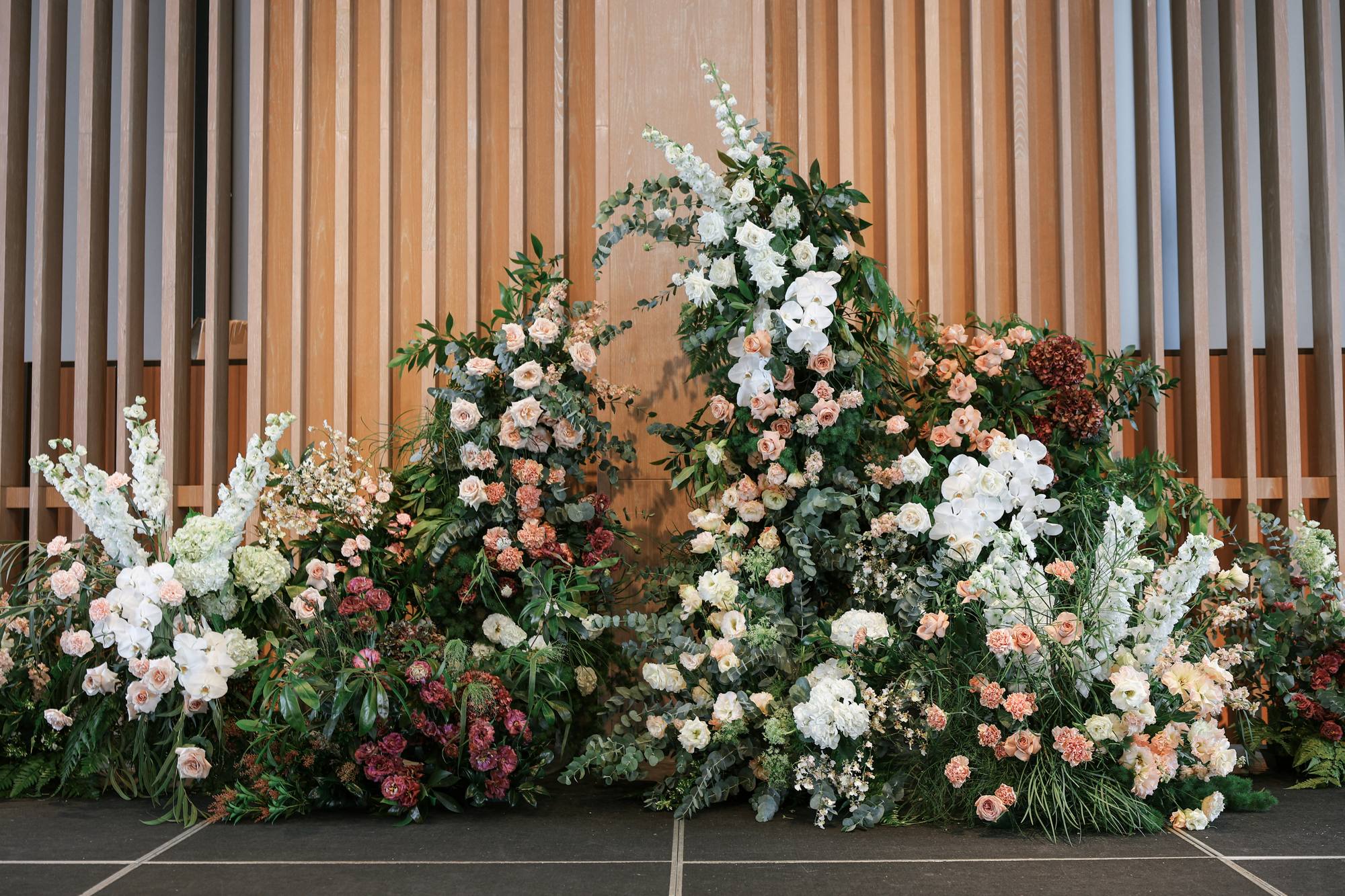 Andaz wedding: meadow style floral installation in antique dusty pink, mauve and rust against wood slats