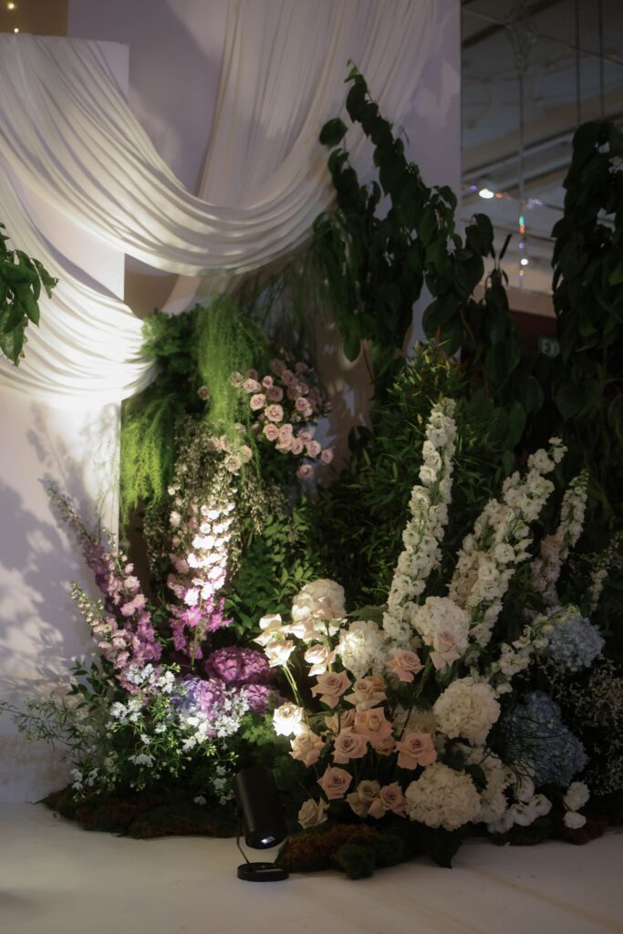 Layered drapery floral installation with cascading greenery, hydrangeas, and soft purple blooms in luxury styling at Shangri-La Singapore