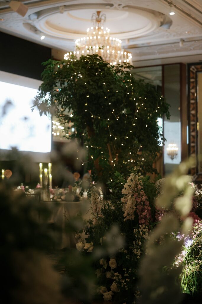 Tall illuminated wedding tree installation with fairy lights and lush greenery framing the ballroom entrance in organic luxury styling at Shangri-La Singapore