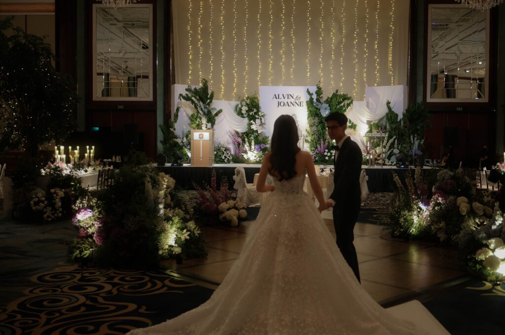 Bride entering through dramatic illuminated tree-lined wedding stage styling with soft floral accents at Shangri-La Singapore