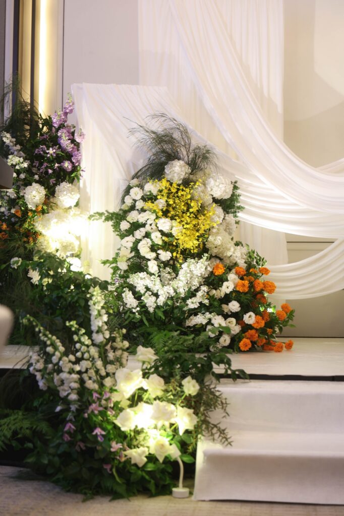 St Regis marigold wedding backdrop installation of marigold, oncidium, white blooms and purple stock