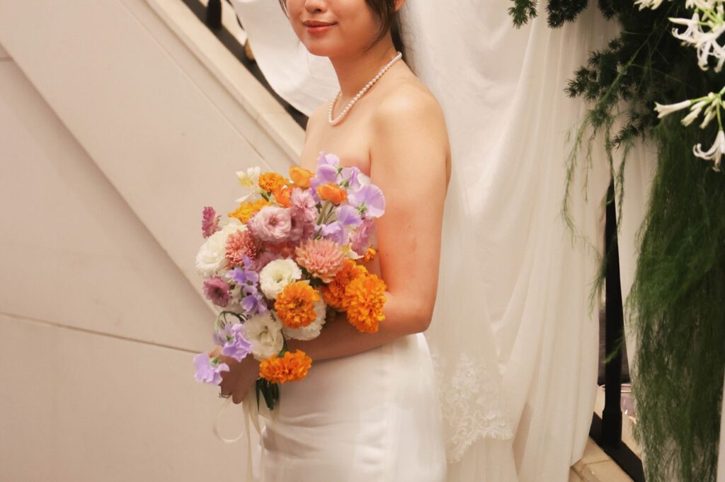 Bride at a St Regis marigold wedding holding a bouquet of marigold, orange and lilac blooms