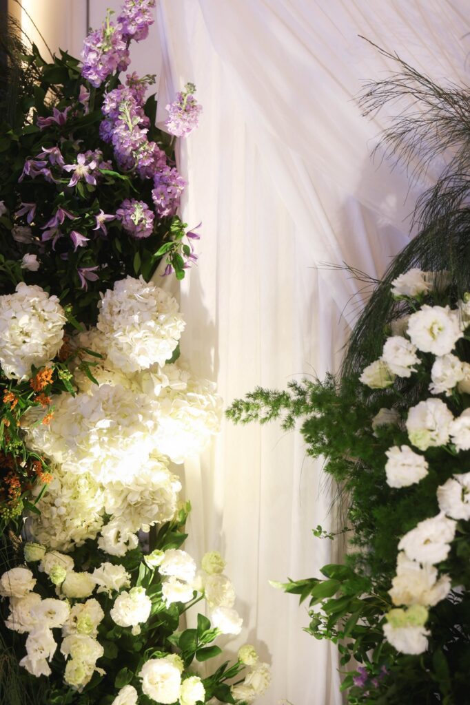 St Regis marigold wedding floral detail of purple stock, white hydrangea and orchid against drapery