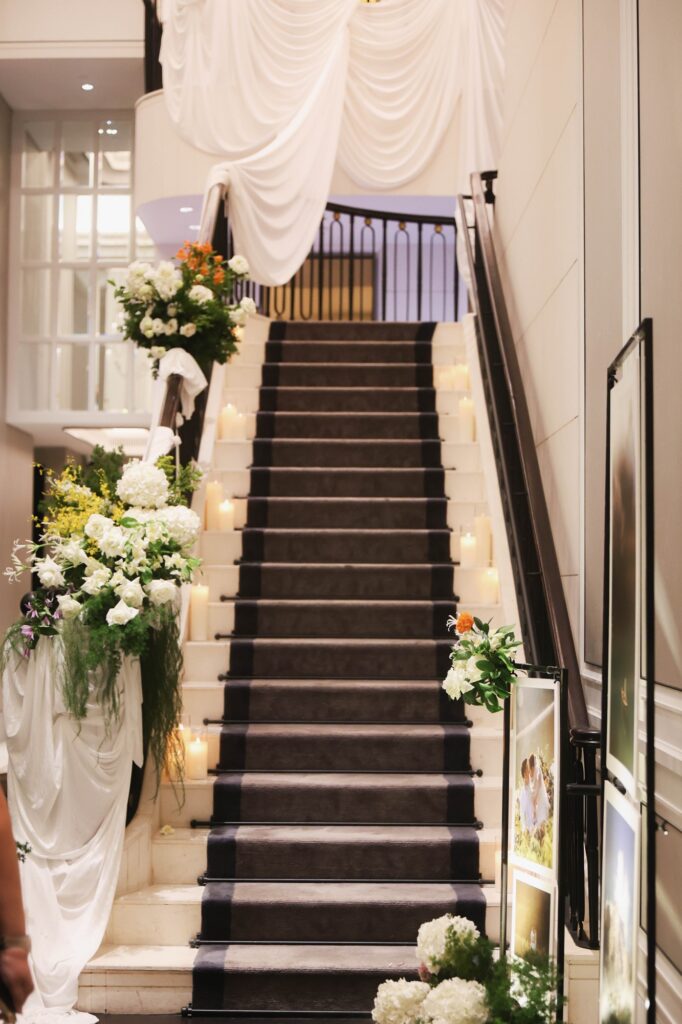 St Regis marigold wedding grand staircase with floral installations at both ends and a photo display