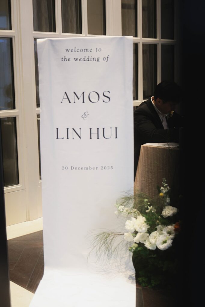 St Regis marigold wedding welcome signage with a small arrangement of white and orange florals