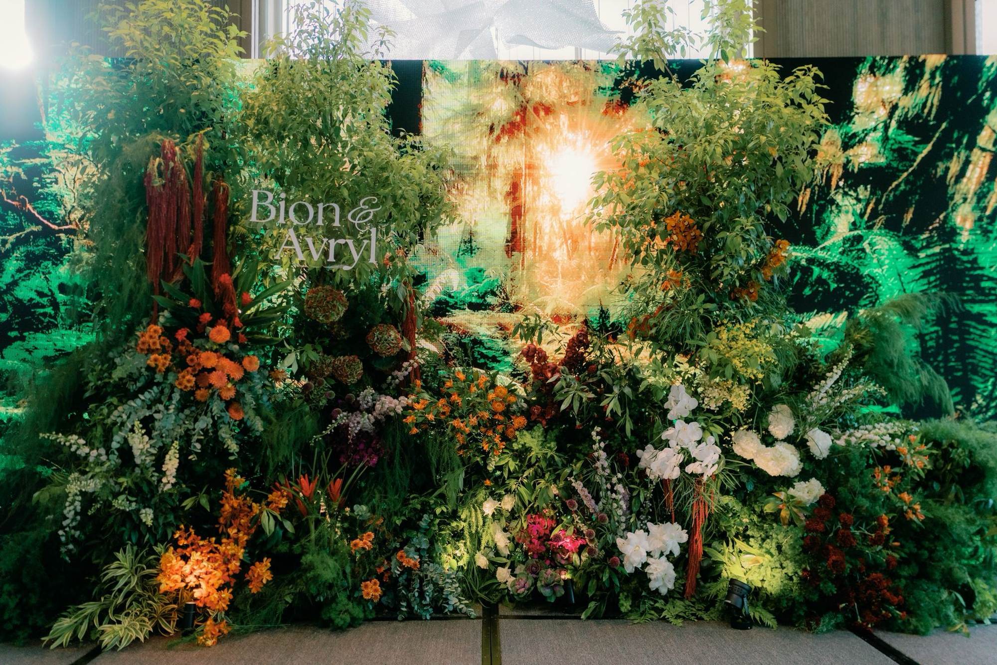 sun-filled forest backdrop layered with orange and burgundy orchids, dahlias and amaranthus