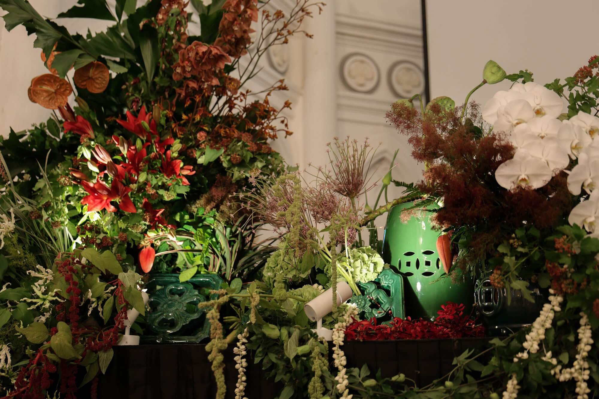 Chijmes wedding: green Peranakan jars with white orchids, red lilies and tropical foliage