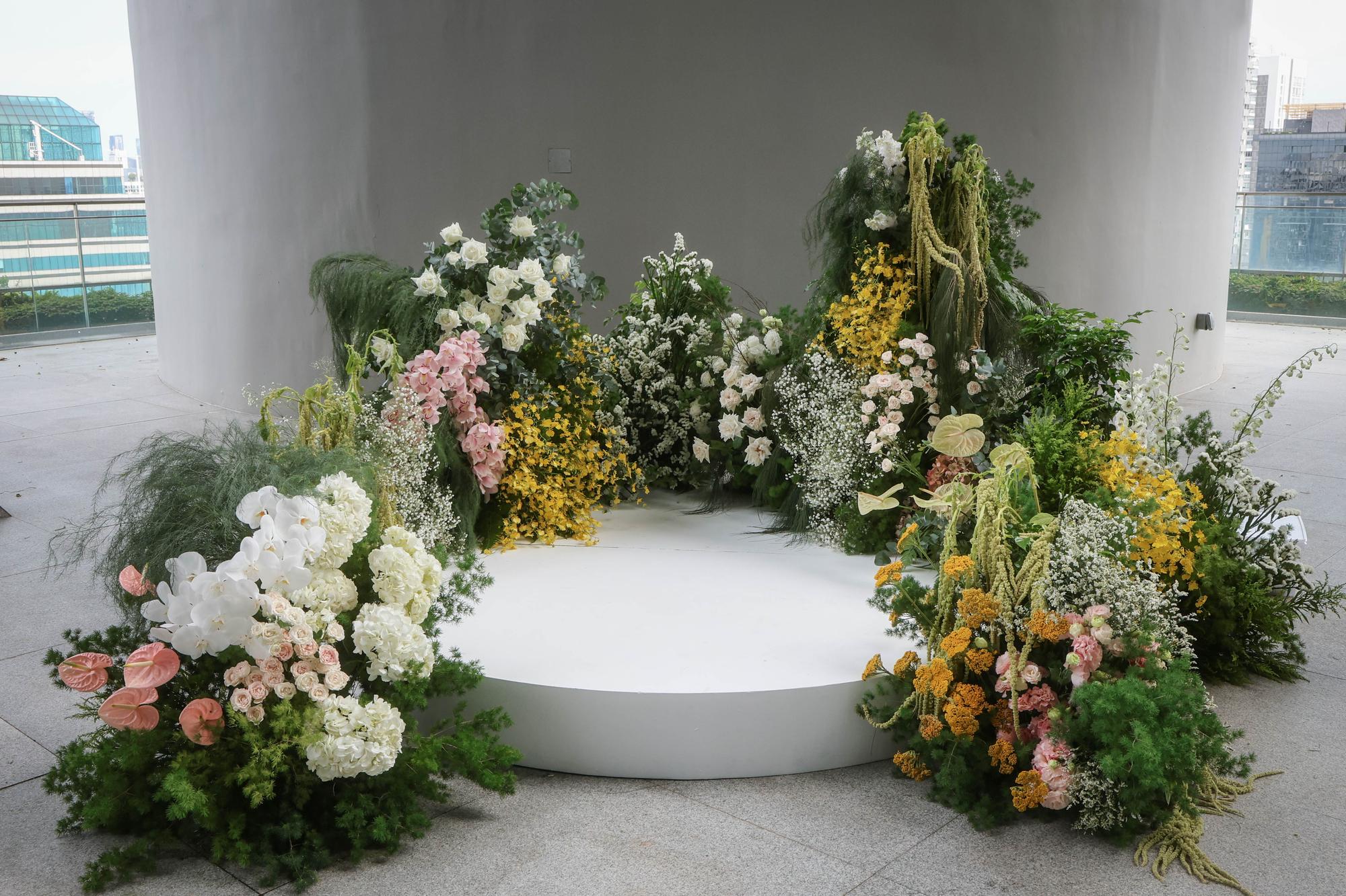 Pan Pacific garden wedding backdrop in yellow, blush pink and white blooms with a round podium